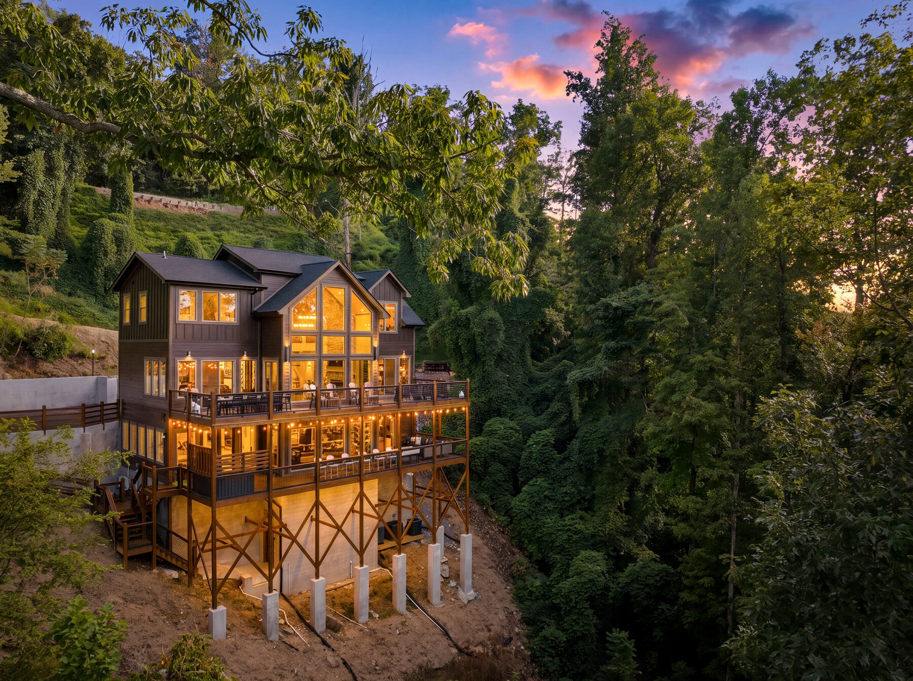 The rear elevation of The Forrest House rising through the trees at sunset
