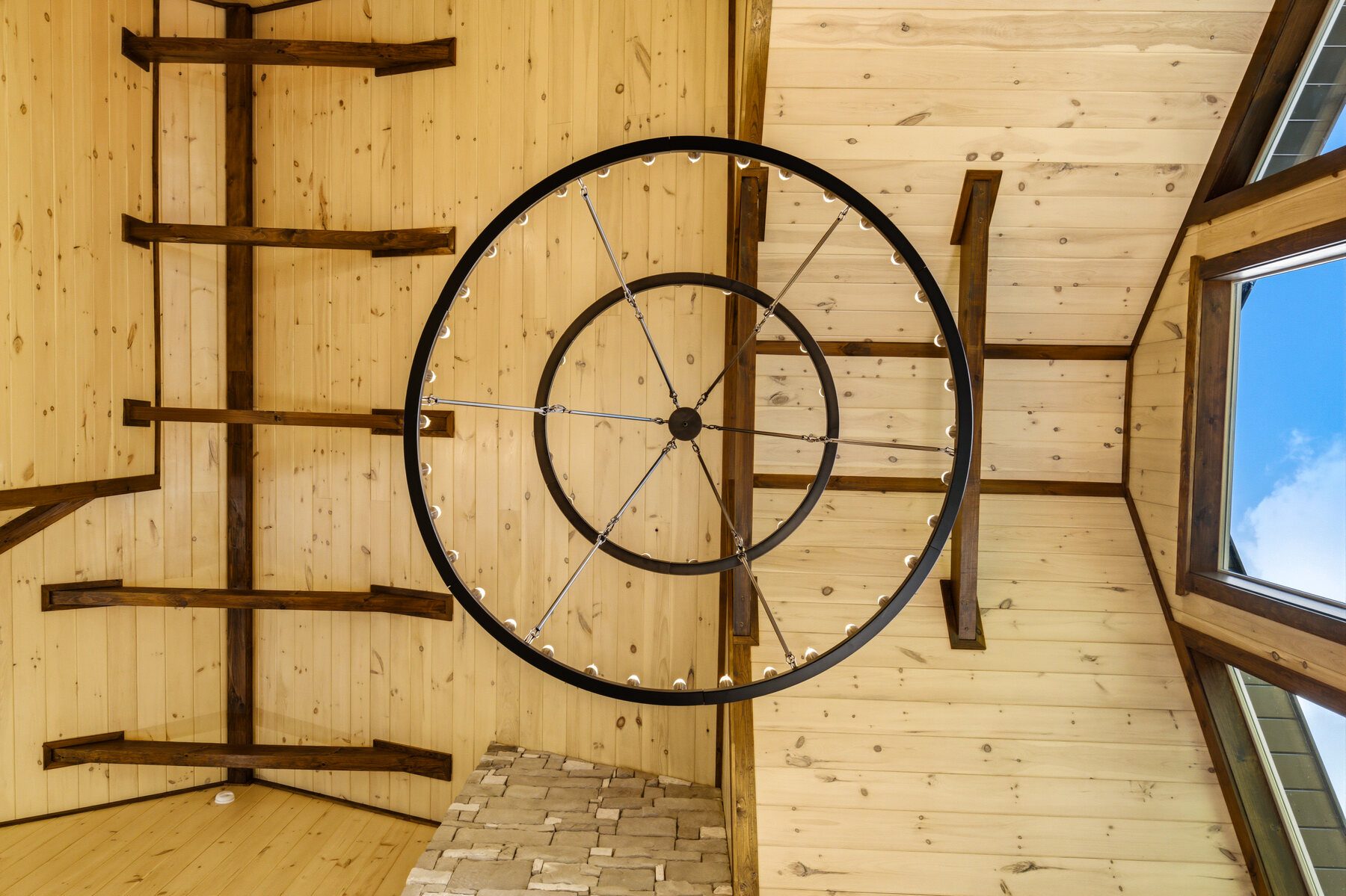 Circular chandelier seen against the timber ceiling