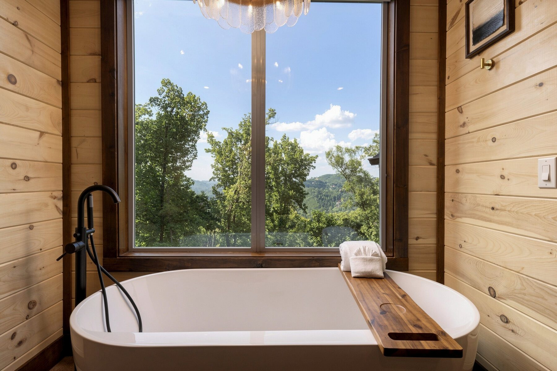 Freestanding bathtub placed directly beneath a mountain-facing window