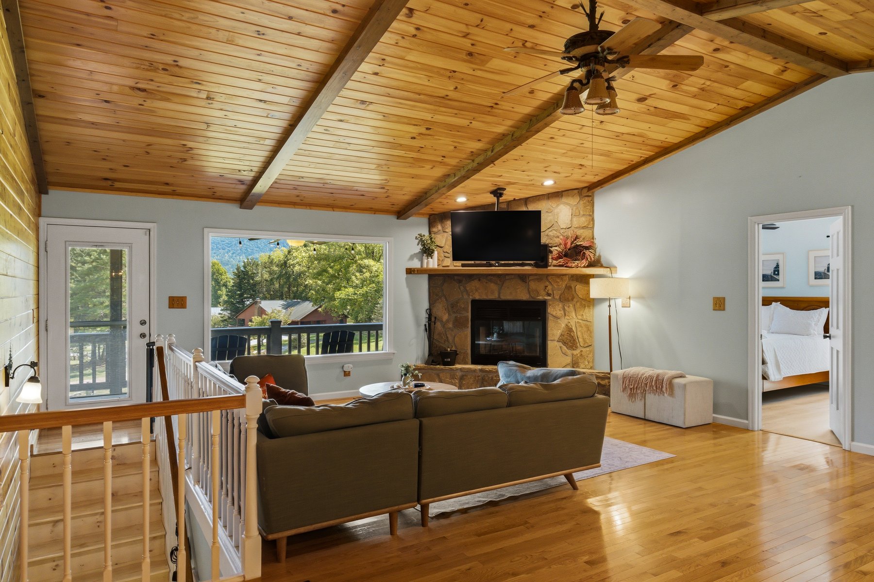 Living room with timber ceiling, stone fireplace, and porch view
