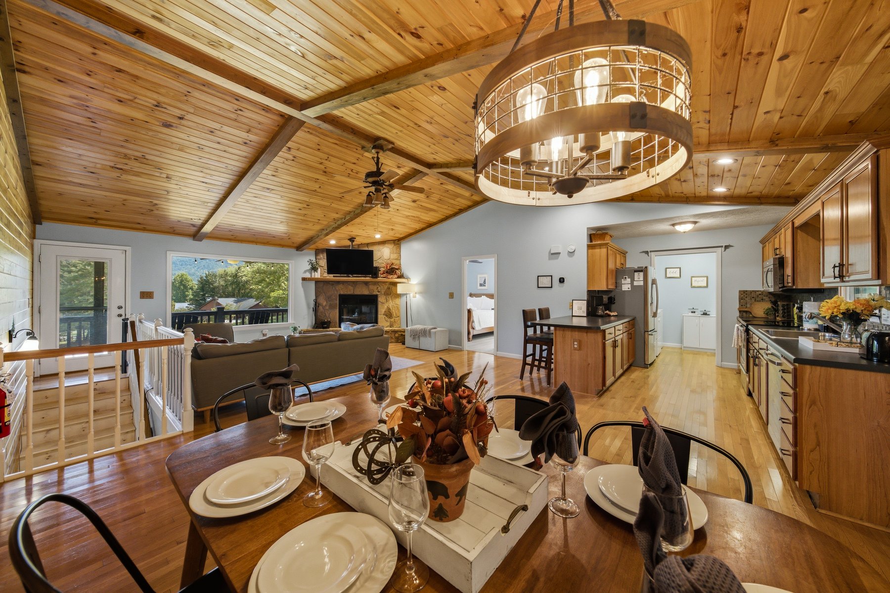 Dining table connecting the living room and kitchen beneath a timber ceiling