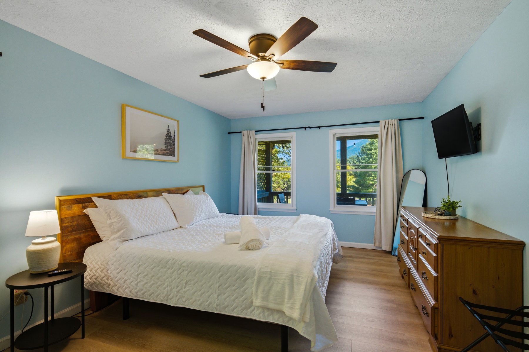 Bright blue bedroom with timber furniture and two windows