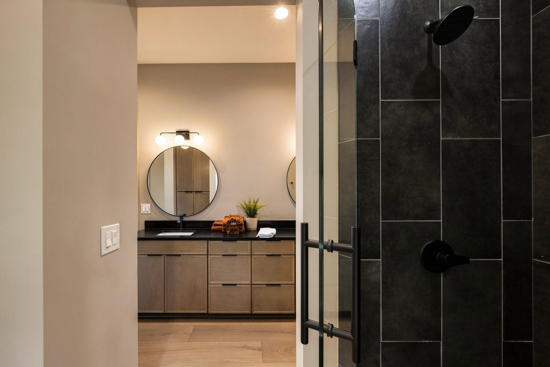 Modern bathroom vanity and dark tiled shower