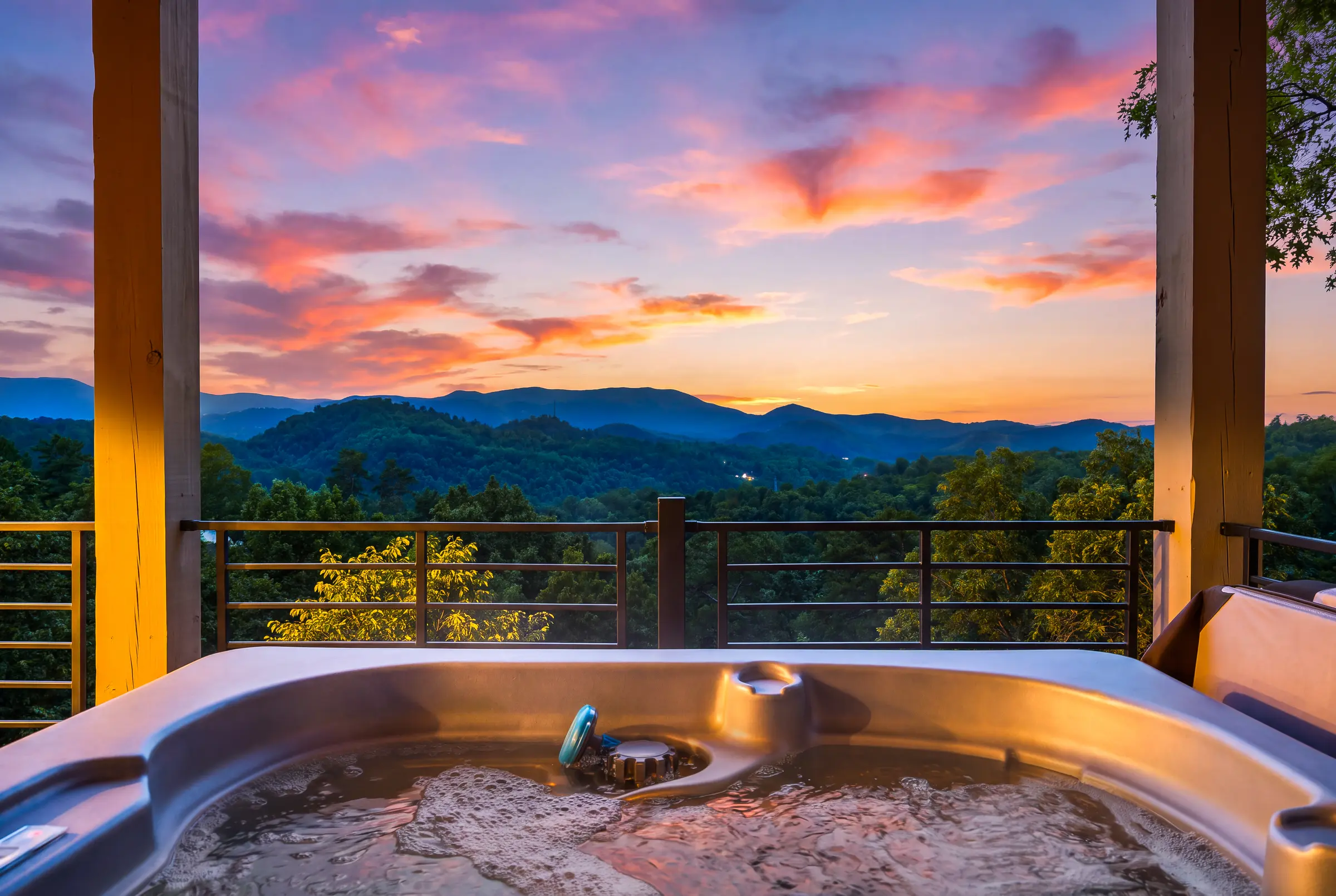 Hot tub overlooking the Smoky Mountains beneath a vivid sunset at Milk and Honey